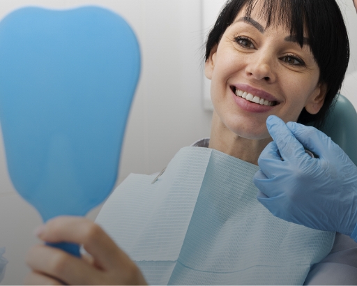 Woman looking in the mirror and smiling after checkup at dentist office stock image